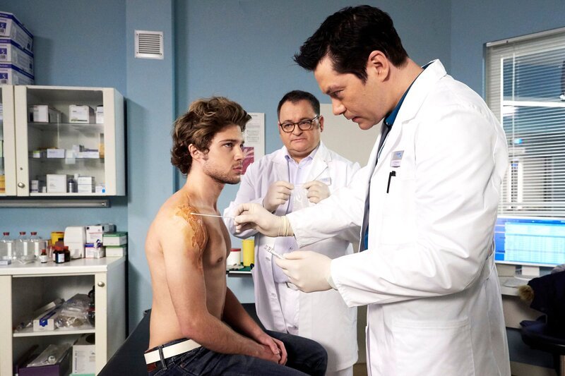 Kris Haas (Jascha Rust, li.) muss regelmäßig seine Brandwunde säubern lassen. Die Heilung verläuft nicht optimal und Kris fragt Dr. Philipp Brentano (Thomas Koch, re.), ob das normal sei. Irgendwas laufe hier doch schief. Philipp versucht ihn zu beruhigen, doch er kann nicht ausschließen, dass sich die Wunde sich infiziert hat. Kris reagiert harsch und ungehalten. Hans-Peter Brenner (Michael Trischan, mi.) muss ihn etwas zügeln. – Bild: MDR/​Saxonia Media/​Wernicke