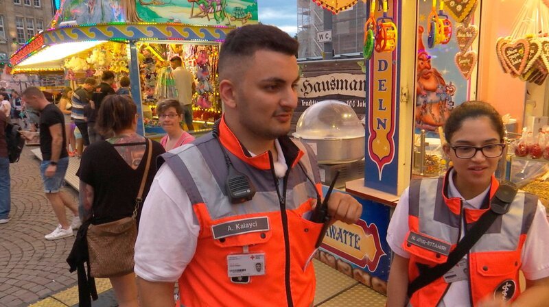 Der Notfallsanitäter Ahmet Kalayci vom Deutschen Roten Kreuz – hier mit einer Kollegin – arbeitet ehrenamtlich auf dem Heinerfest Darmstadt. – Bild: HR