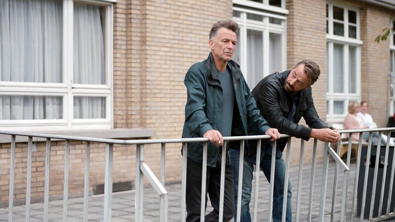 Der Undercover-Polizist Bob Lemmens (Tom Waes, r.) versucht John Zwart (Raymond Thiry) davon zu überzeugen, dass er bei der Suche nach Gino Maldini eine große Hilfe wäre. – Bild: De Mensen /​ ZDF und De Mensen