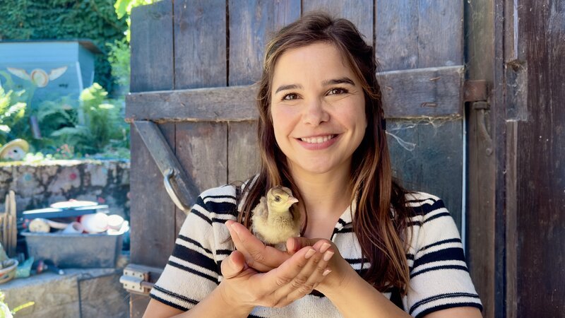 Anna darf ein flauschiges Pfauenküken auf die Hand nehmen. – Bild: BR/​TEXT+BILD Medienproduktion GmbH & Co. KG/​Katharina Brackmann