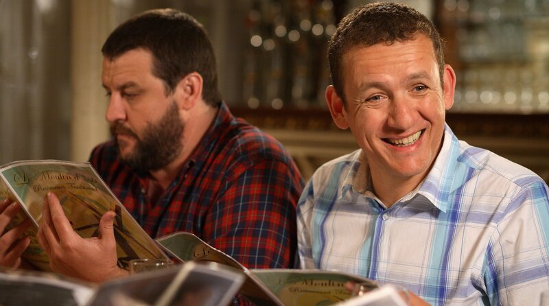 Die Kollegen Yann (Guy Lecluyse, li.) und Antoine (Dany Boon) versuchen beim gemeinsamen Abendessen ihrem Chef Philippe den örtlichen Dialekt Ch’ti beizubringen. – Bild: rbb/​Hirsch-Pathe Renn Production/​TF1 Films Productions/​Les Productions du Ch’timi/​CRRAV Nord Pas de Calais
