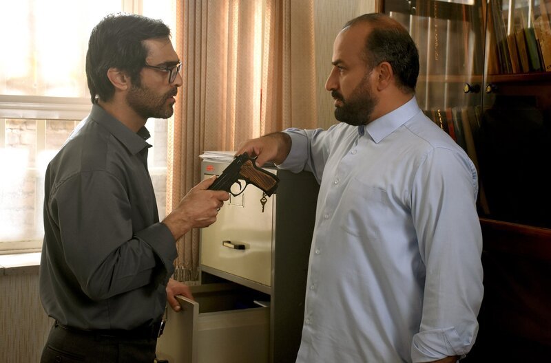 Das Verschwinden von Imans (Misagh Zare, re.) Dienstwaffe löst eine Kette aus Misstrauen, Kontrolle und Gewalt gegenüber der eigenen Familie aus. – Bild: Films Boutique Das Verschwinden von Imans (Misagh Zare, re.) Dienstwaffe löst eine Kette aus Misstrauen, Kontrolle und Gewalt gegenüber der eigenen Familie aus. – Bild: Films Boutique