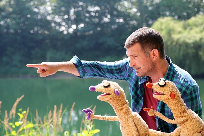 Der Reiseführer (Simon Böer) zeigt Jan & Henry den See. – Bild: NDR/​bigSmile