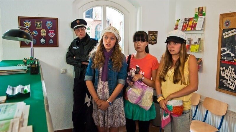 Emma (Sophie Karbjinski) versucht bei der Lüneburger Polizei das Problem zu erklären. V.l.: Officer (Oliver Sauer), Emma, Jackie (Charlotte Nicdao) und Ally (Marny Kennedy). – Bild: NDR/​Southern Star