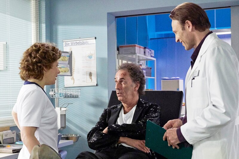 Als Frank Butze (Hugo Egon Balder, mi.) in der Sachsenklinik von Schwester Ulrike (Anita Vulesica, li.) als der berühmte Franky Alexander erkannt wird, staunt Dr. Martin Stein (Bernhard Bettermann, re.) nicht schlecht. Als die beiden dann auch noch gemeinsam in Frankys einzigen großen Hit einstimmen und miteinander flirten, muss Martin kurz daran erinnern, dass Franky zusammengebrochen sit und dass Martin ihn gern untersuchen würde. – Bild: MDR/​Saxonia/​Wernicke