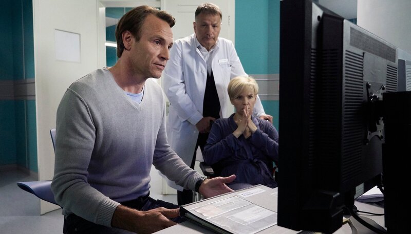 Dr. Martin Stein (Bernhard Bettermann, li.), der eigentlich beurlaubt ist, hat sich heimlich Dr. Kathrin Globischs (Andrea Kathrin Loewig, re.) Akte mitgenommen. Er kommt zu dem Ergebnis, dass es sich bei Kathrin auch um einen Tumor am Herzen handeln könnte. Kathrin bittet Dr. Roland Heilmann (Thomas Rühmann, mi.) Martin miteinzubeziehen. Und tatsächlich, das MRT zeigt einen Tumor. Die gute Nachricht ist, dass es sich sehr wahrscheinlich um ein gutartiges Myxom handelt, die schlechte: Die Operation ist äußerst riskant. Die besten Chancen, den Tumor vollständig zu entfernen, verspricht ein Ex-situ-Verfahren, eine OP-Methode, bei der das Herz aus dem Körper entnommen wird. – Bild: MDR/​Saxonia Media/​Wernicke