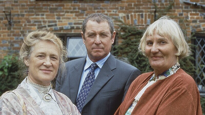 Inspector Barnaby (John Nettles, M.) erfährt bei seinen Ermittlungen in Midsomer Parva interessante Details von den Schwestern Alice (Merelina Kendall, l.) und Marian Leonard (Charmian May, r.), die das Postamt des Ortes führen. – Bild: ZDF und All3Media