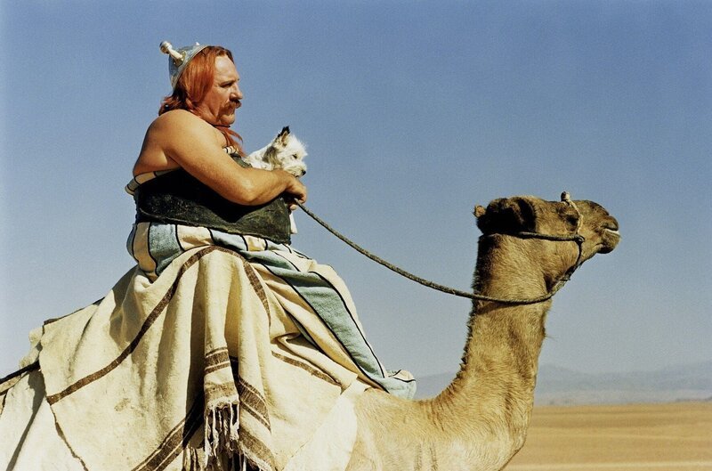 Nur nicht seekrank werden: Obelix (Gérard Depardieu) hofft, dass sein kleiner Hund Idefix die Reise auf dem Kamel gut übersteht. – Bild: RTL /​ © Tobis StudioCanal