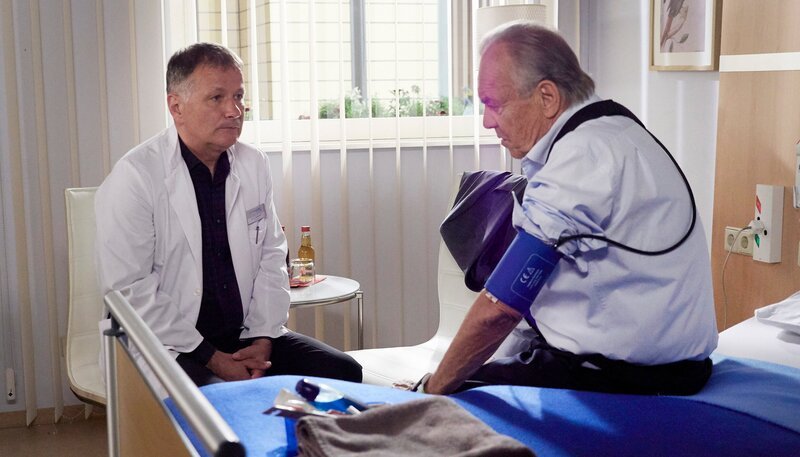 Professor Gernot Simoni (Dieter Bellmann, re.) kommt eine Woche zu früh zu seinem Gesundheitscheck in die Sachsenklinik. Dr. Roland Heilmann (Thomas Rühmann, li.) durchschaut seinen ehemaligen Chef sofort und ist gerührt, dass er sich nach dem Tod von Rolands Frau Sorgen um ihn macht. So sehr sich Roland in seiner Trauer vom Rest der Welt abkapselt, schafft es Simoni doch, einen Zugang zu ihm zu finden. Roland bittet ihn sogar um Ratschläge. – Bild: MDR/​Saxonia Media/​Wernicke