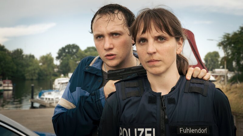 Der gewaltbereite Aktivist Robert „Robbie“ Lichtenberg (Michelangelo Fortuzzi), hat Dorfpolizistin Lesly Fuhlendorf (Caroline Erikson) als Geisel genommen und will seine Freundin Nina damit frei bekommen. – Bild: Christine Schroeder /​ ZDF
