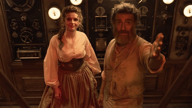 Humility (Georgia Flood, l.) lässt sich von Benoit (Thierry Frémont, r.) genau erklären, wie die Nautilus funktioniert. – Bild: ZDF und Vince Valitutti/​Disney+