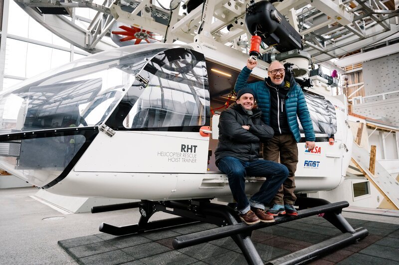 Von links: Sebastian Bezzel und Simon Schwarz, am Hubschrauber. – Bild: Schelke Bonnetsmüller /​ BR/​Film Five GmbH
