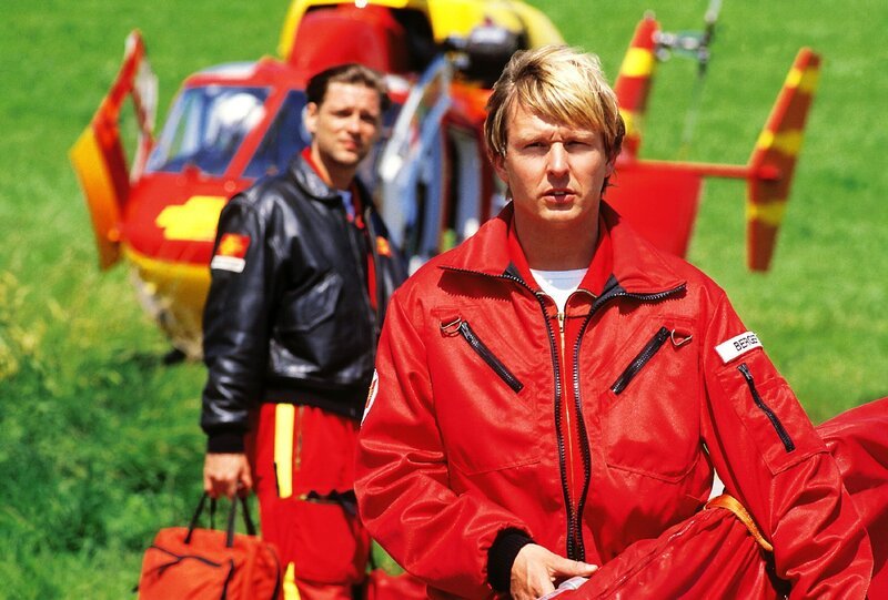Pilot Thomas Wächter (Manfred Stücklschwaiger, hi.li.) und Sanitäter Peter Berger (Serge Falck) sind am Unfallort angekommen. – Bild: RTLplus /​ Helene Waldner
