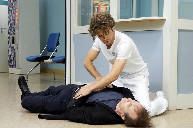 Götz Neumeier (Arnfried Lerche, liegend) soll die Rollen seines Freundes und Kollegen Joseph Bernau am Theater übernehmen, solange dieser in der Klinik liegt. Doch Götz ist dem Ganzen nicht gewachsen und bricht noch vorm verlassen der Sachsenklinik zusammen. Kris Haas (Jascha Rust, oben) ist sofort zu Stelle. – Bild: MDR/​HA Kommunikation