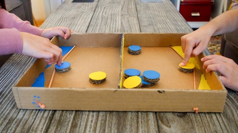 Kartonspaß mit einem selbstgebastelten Flipper: Clara und Sofia müssen jetzt ganz schnell sein beim Versuch, alle Chips ihrer Farbe auf das gegnerische Feld zu katapultieren! Wer schneller ist, hat gewonnen! – Bild: ORF/​Tower10