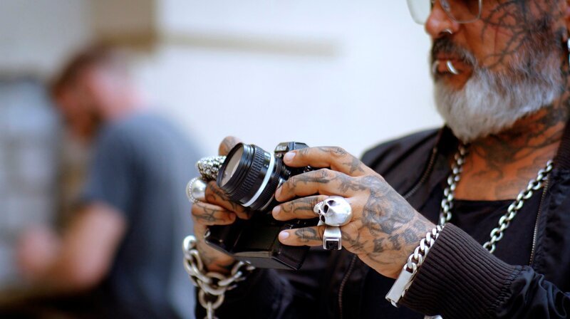 Als junger Fotograf porträtierte Sven Marquardt unübertroffen die Ostberliner Prenzlauer-Berg-Bohème in gotischem schwarz/​weiß. Nach dem Mauerfall legt er ein paar Jahre die Kamera bei Seite und taucht ins Nachtleben ab. Sein Charisma und die Arbeit an der Tür des Berghain, das in der internationalen Clubszene Kult-Status erlangt, machen ihn weltberühmt. – Sven Marquardt. – Bild: rbb/​itworks
