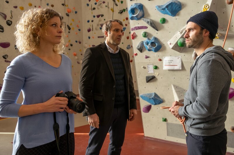 Ein unverhoffter Besuch wirft Eric Du Bois (Jonathan Müller, r.), sowie Birgit (Anna Schäfer) und Marco Verlinden (Stefan Rudolf, M.) kurz vor der Eröffnung ihrer Kletterhalle für einen Moment aus der Bahn. – Bild: Erika Hauri /​ ZDF