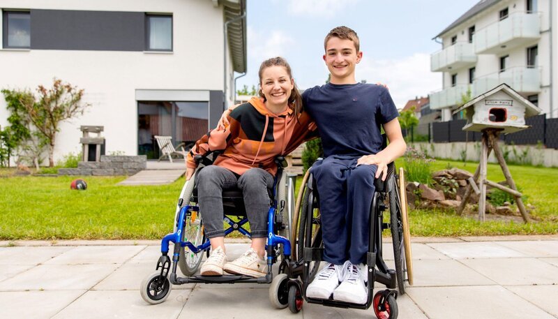 Checkerin Marina lernt Rollstuhlfahren von Janis, der im Rollstuhl unterwegs ist. – Bild: BR/​megaherz gmbh/​Marcus Lehmann