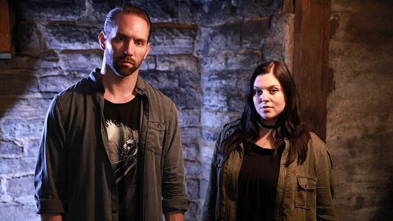 Hosts Nick Groff and Katrina Weidman stand in front of basement brick wall. – Bild: Discovery Communications