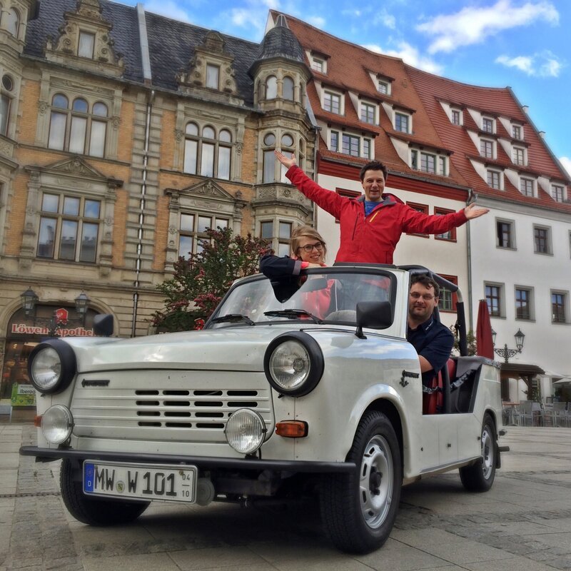 Unterwegs in Sachsen: Die Reporter Esther Brandt (links) und André Gatzke (Mitte) treffen in Zwickau u.a. Trabbi-Fans. – Bild: BR/​WDR/​tvision
