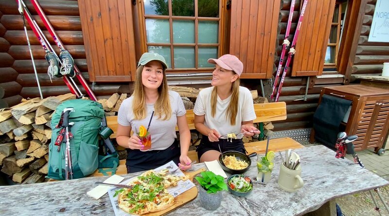 Einkehr nach 30 Kilometern in zwei Tagen. Die Wander-Influencerinnen Liz (l) und Marina stärken sich nach ihrer Wanderung auf dem Rothaarsteig. – Bild: WDR/​Julia Feldhagen