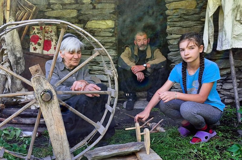 Die Urenkeltochter Gvantsa Tsiklauri (re.) ist für ein religiöses Fest zu Besuch bei ihrer Uroma Sandua (li.) und ihrem Opa Paata Tsiklauri (Mi.). – Bild: Manuel Daubenberger
