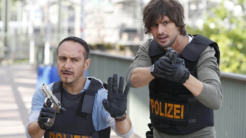 Semir (Erdogan Atalay, l.) und Ben (Tom Beck) konnten Schäffer zwar in die Enge treiben, doch nun droht er ihnen mit einer Handgranate … – Bild: TVNOW /​ Guido Engels