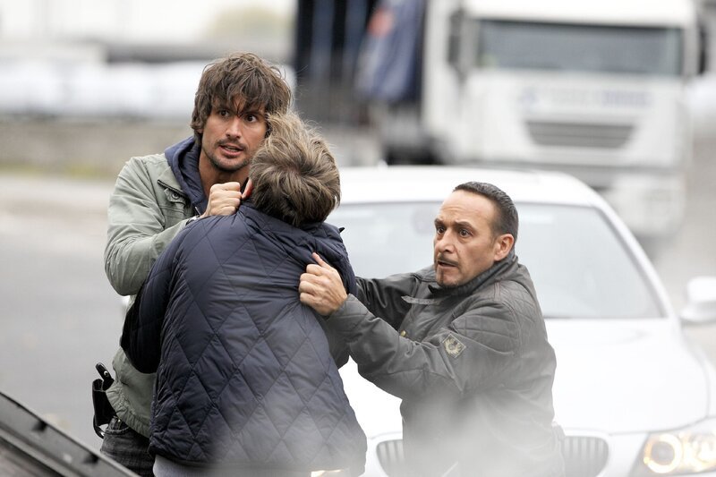 Ben (Tom Beck, li.) und Semir (Erdogan Atalay, re.) ziehen Manuel (Jan Henrik Stahlberg) aus dem Unfallwagen und bemerken, wie das Boot mit Eva und Franziska an Bord aus dem Hafenbecken katapultiert wird … – Bild: RTL NITRO /​ Guido Engels