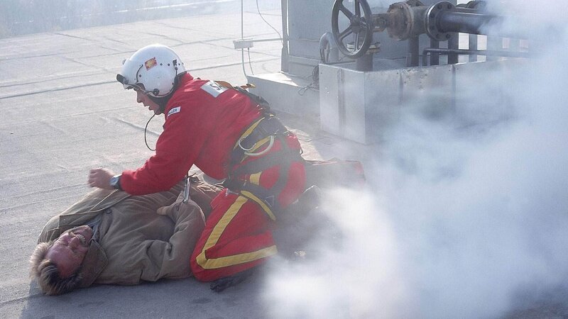 Werksleiter Gruber (Hermann Giefer) liegt nach dem Rückstoss durch das Gas verkrampft auf dem Dach. Sanitäter Ralf Staller (Wolfgang Krewe) leistet erste Hilfe. – Bild: MG RTL D /​ Helene Waldner