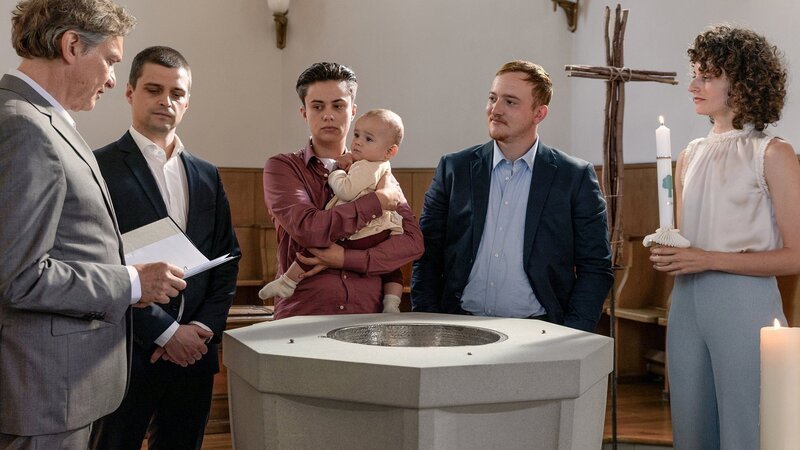 Die Familie ist an der Taufe friedlich vereint, v.li.: Pfarrer, Julian Koechlin als Michi Wyss, Rumo Wehrli als Liam Belucci, Jérôme Humm als Lorenz Wyss, Sophie Hutter als Sarah Wyss – Bild: SRF/​Sava Hlavacek
