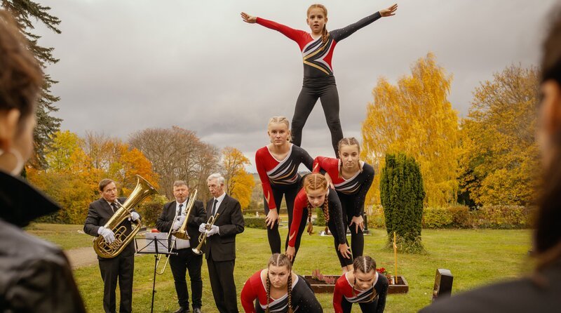  Die Turngemeinschaft SV Gerlau und die Gerlauer Spatzen erweisen Rolf auf dem Friedhof die letzte Ehre. Links: Gerald (Horst Kotterba), Lilly (Amy Binder), Lotti (Gina Binder)  – Bild: ARD Degeto Film/​Adrian Gross /​ ARD Degeto/​Programmplanung und P