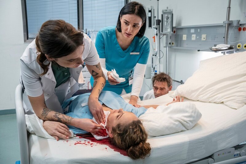 Ella (Ines Quermann, 2.v.l.) bricht sofort zusammen, nachdem Wolfgang (Martin Feifel) sie unerwartet attackiert hat. Dr. Leonie Mertens (Linda Marlen Runge, l.) und Nora (Mimi Fiedler, M.) versuchen verzweifelt die Lage unter Kontrolle zu bringen. – Bild: TVNOW