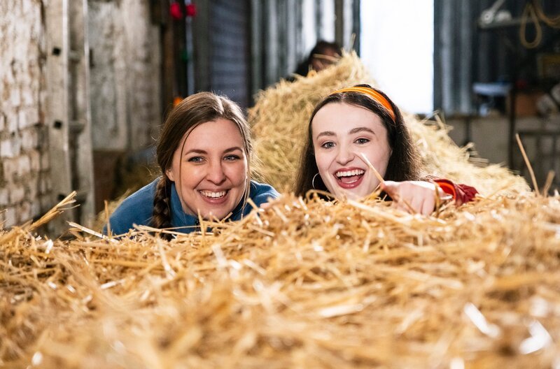 Von links: Sophia (Patricia Freund) und Maja (Godiva Adela) freuen sich, als sie Stadlbauer erfolgreich in Sachen Hühner getratzt haben. – Bild: BR/​Lena Semmelroggen