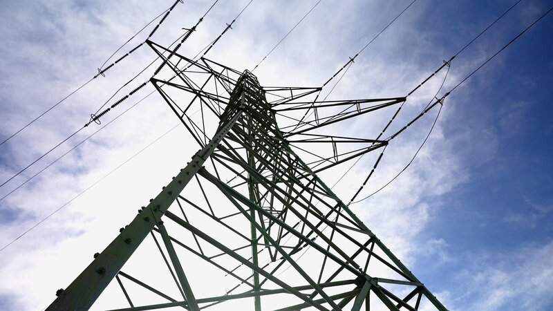 Blick von unten auf einen Starkstrommast. – Bild: SRF