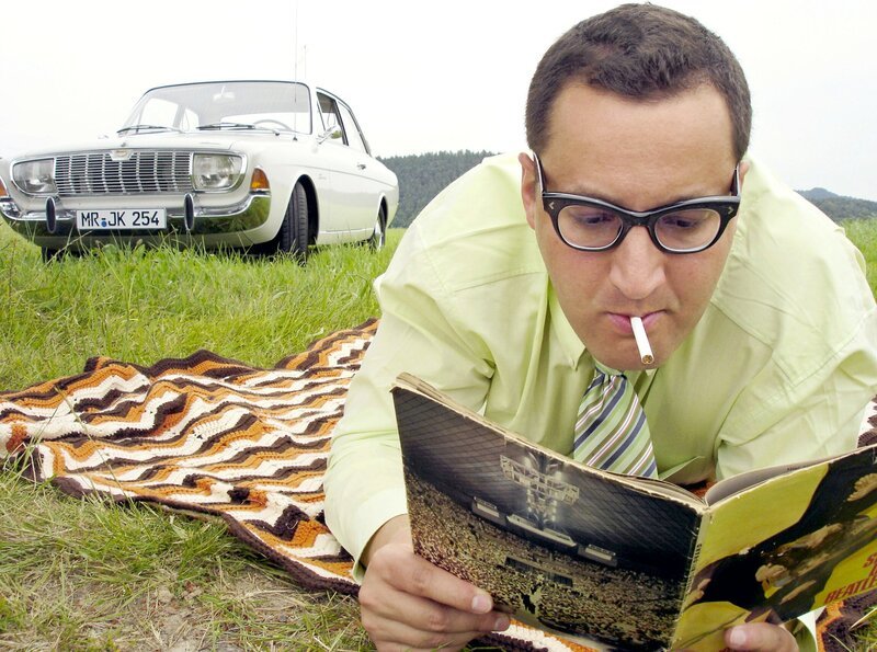 Ferdinand Kilian (Robert Kratz) träumt vom kommenden Auftritt der Beatles in Marburg. Im Hintergrund sein stadtbekannter Ford 17M. – Bild: HR/​Michael Wulfes Filmproduktion München