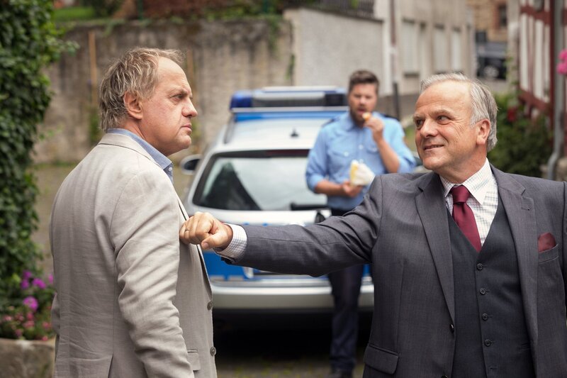 Nach einer anstrengenden Nacht ist Killmer (Uwe Ochsenknecht, links) noch nicht wieder ganz auf der Höhe. Er fragt sich, ob es etwas zu bedeuten hat, dass Bürgermeister Drömmer (Bernhard Schütz) ihm zur Hochzeit gratuliert? – Bild: SWR/​Thomas Kost