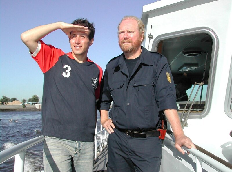 Willi Weitzel mit einem Zollbeamten auf dem Zollschiff im Hamburger Hafen. Mit ihnen ist Willi unterwegs, um einen Bananenfrachter aus Kolumbien auf Schmuggelware zu durchsuchen. – Bild: Bayerischer Rundfunk/​megaherz gmbh