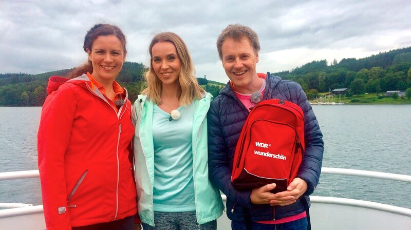 „Wunderschön“-Ruhrradler Anne Willmes und Stefan Pinnow treffen Ruhrtalradweg-Expertin Sandra Wolfson (Mitte) am Hennesee. – Bild: Tarja Kühne /​ BR, WDR