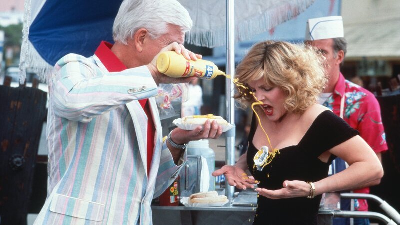 Lt. Drebin (Leslie Nielsen) gerät von einem Fettnäppchen ins nächste.. (Foto, li.: Priscilla Presley) – Bild: RTLZWEI