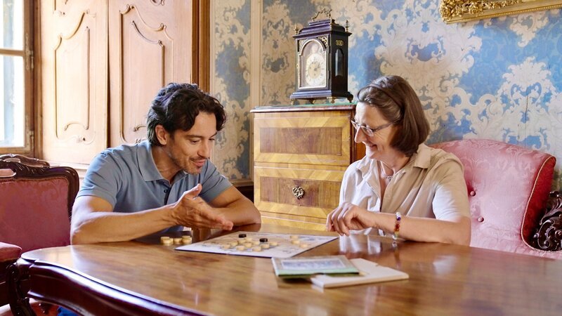 Von Gräfin Elisabeth Kuefstein erhält Stefano Bernardin auf Schloss Greillenstein charmante Nachhilfe in „Strategie“. – Bild: ORF/​ORF-Niederösterreich