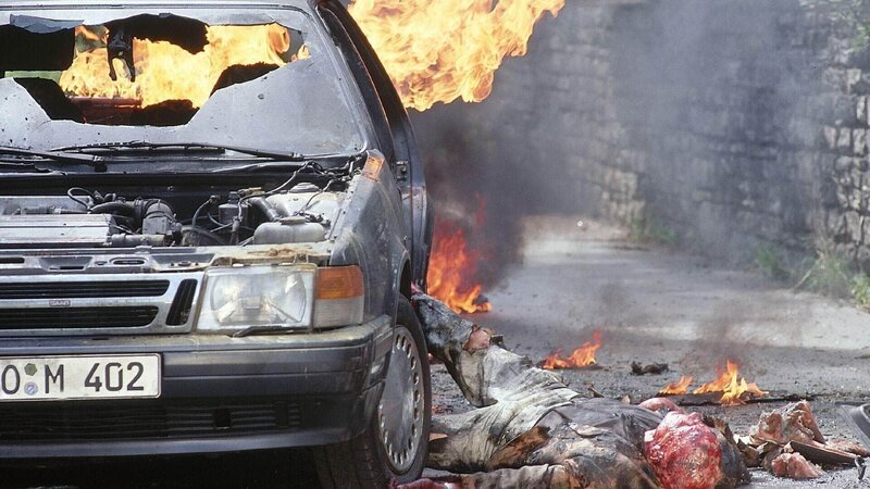 Kaminsky (Hans Peter Hallwachs) ist durch die Wucht der Explosion aus dem Auto geschleudert worden und bleibt schwer verletzt liegen. – Bild: RTL /​ Helene Waldner