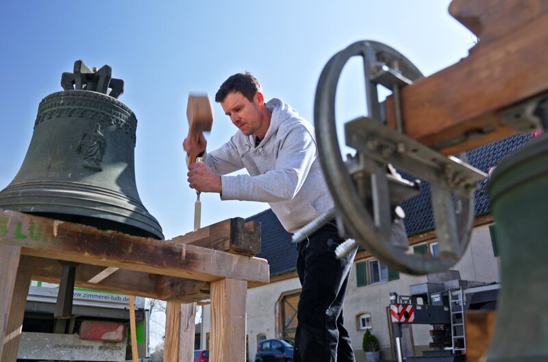 Glockenspezialist Simon Westermann bearbeitet das Joch der Kirchenglocke. – Bild: SWR/​teamWERK/​Dirk Schwarz