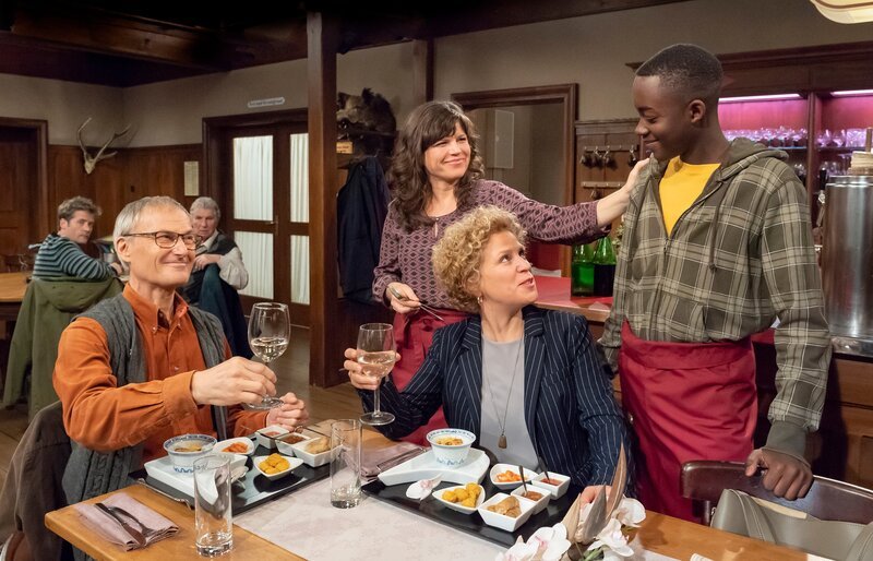 Tayo (Charles Henri Junior Sehba, re.) kommt in den Löwen zum Arbeiten und verdient sein erstes Geld. Karl (Peter Schell, li.) und Bea (Christiane Brammer) sind stolz auf ihn. Und Eva (Lucie Muhr, stehend) hat Hilfe. – Bild: SWR/​Alexander Kluge