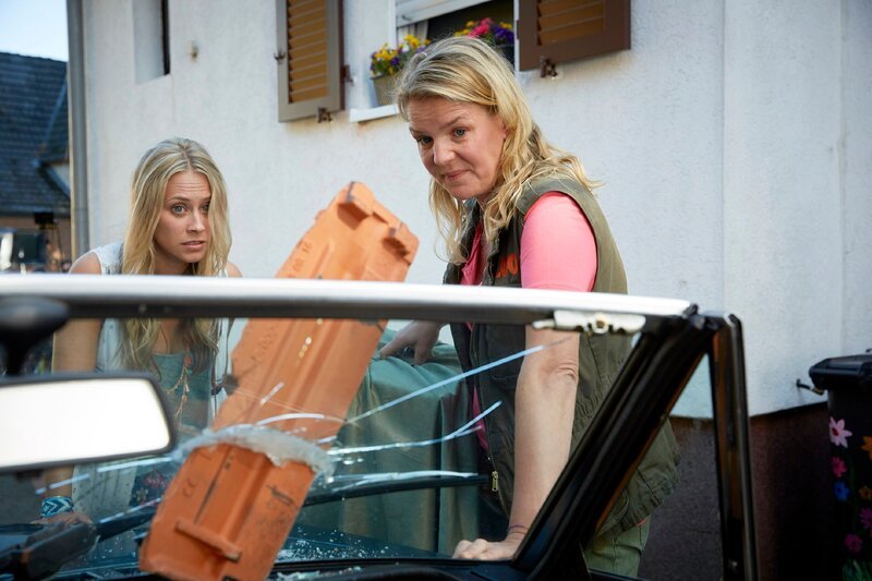 Toni (Sina Tkotsch, l.) ist ein Dachziegel in die Scheibe des Oldtimers von Nachbar Kurt Koslowski gekracht. Eva (Mirja Boes) begutachtet den angerichteten Schaden. – Bild: TVNOW /​ Guido Engels