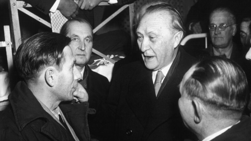 Als Konrad Adenauers größten Verdienst gilt die Heimholung der letzten 10.000 Kriegsgefangenen aus russischen Lagern – zehn Jahre nach Kriegsende. – Konrad Adenauer (2.v.r.) im Durchgangslager Friedland, Niedersachsen, 1954. Adenauer im Gespräch mit Heimkehrern nach ihrer Freilassung aus sowjetischer Kriegsgefangenschaft. – Bild: WDR/​akg