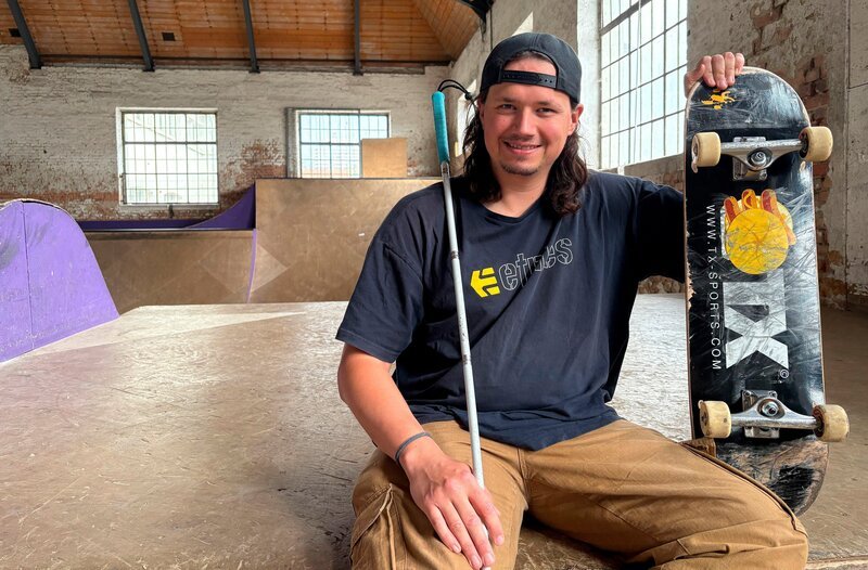 Johannes im Porträt mit Skateboard und Blindenstock. – Bild: BR/​Maximus Film/​Laura Fischbach