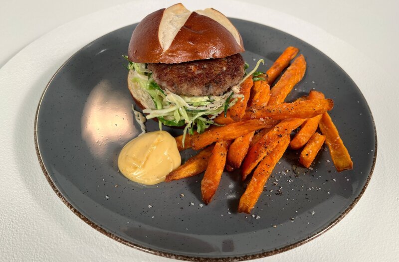 Hans-Jörg Bachmeier kocht Laugenburger mit Schweinswürstl Patty, bayerischem Cole Slaw und Süßkartoffel-Pommes. – Bild: BR/​Asijeh Nikazar