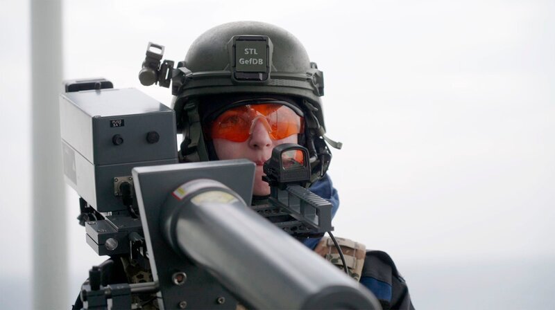 Eine Soldatin zielt mit einem „Drone-Buster“ auf eine anfliegende Drohne. – Bild: NDR/​Lennart Banholzer