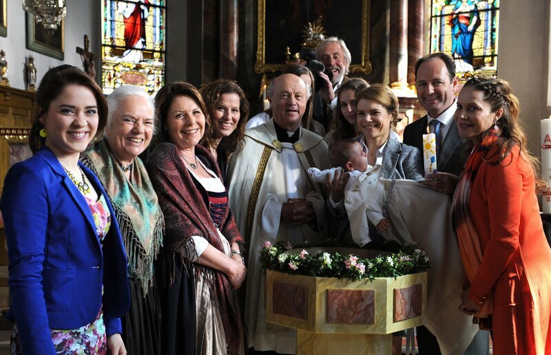 Nach Franzis Taufe posieren die Lansinger für das Foto. Von links: Katharina Benninger (Carina Dengler), Theresa Brunner (Ursula Erber), Rosi Brunner (Brigitte Walbrun), Annalena Brunner (Heidrun Gärtner), Vinzenz Kurz (Hans Stadlbauer), Martin Kirchleitner (Hermann Giefer), Franzi (Franzi), Uschi Guggenmoser (Silke Popp), Hubert Kirchleitner (Bernhard Ulrich) und Trixi Preissinger (Doreen Dietel). – Bild: BR/​Marco Orlando Pichler