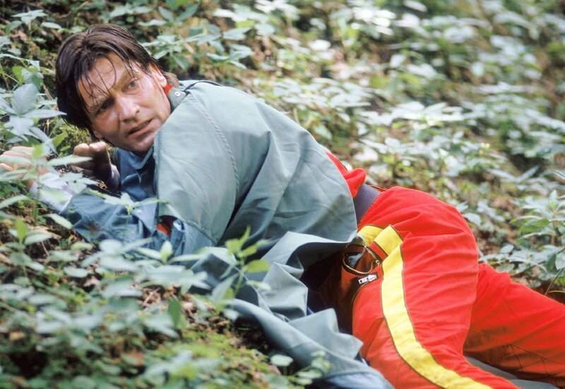 Dr. Lüdwitz (Rainer Grenkowitz) versteckt sich im Unterholz. Die Killer der Russenmafia sind ihm dicht auf den Fersen. – Bild: RTL Passion